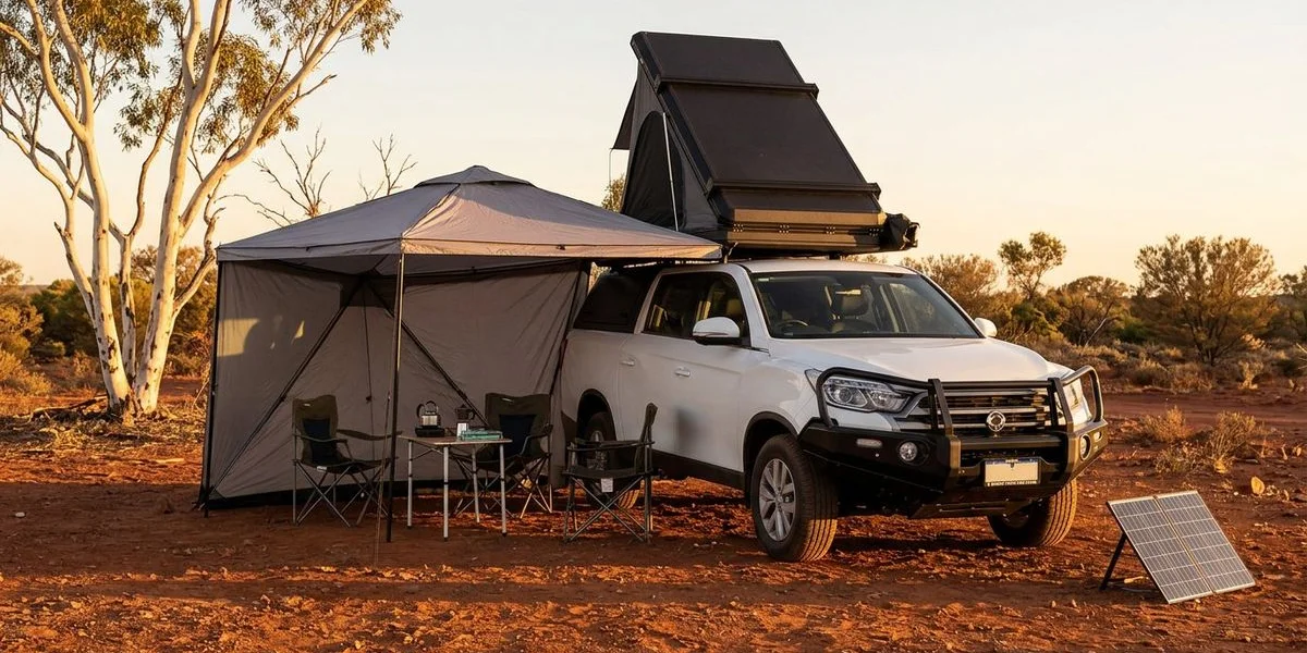 A fully equipped 4WD camper parked at a remote red dirt campsite in the Western Australian outback with camping gear set up and golden hour lighting